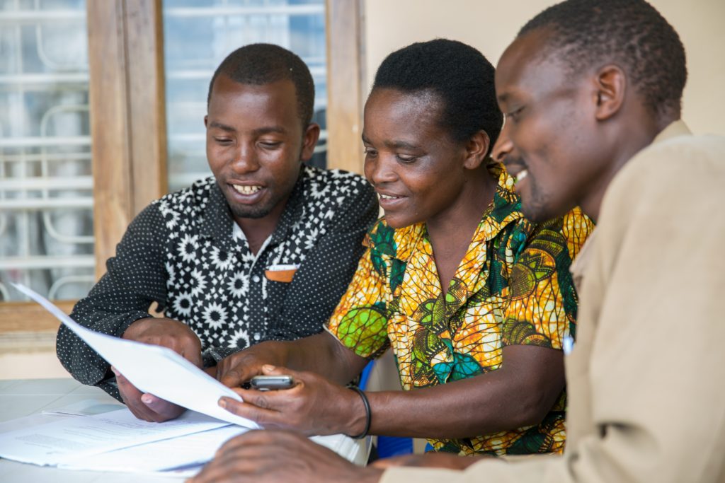 Three men sitting at a table and looking at documents in Tanzania