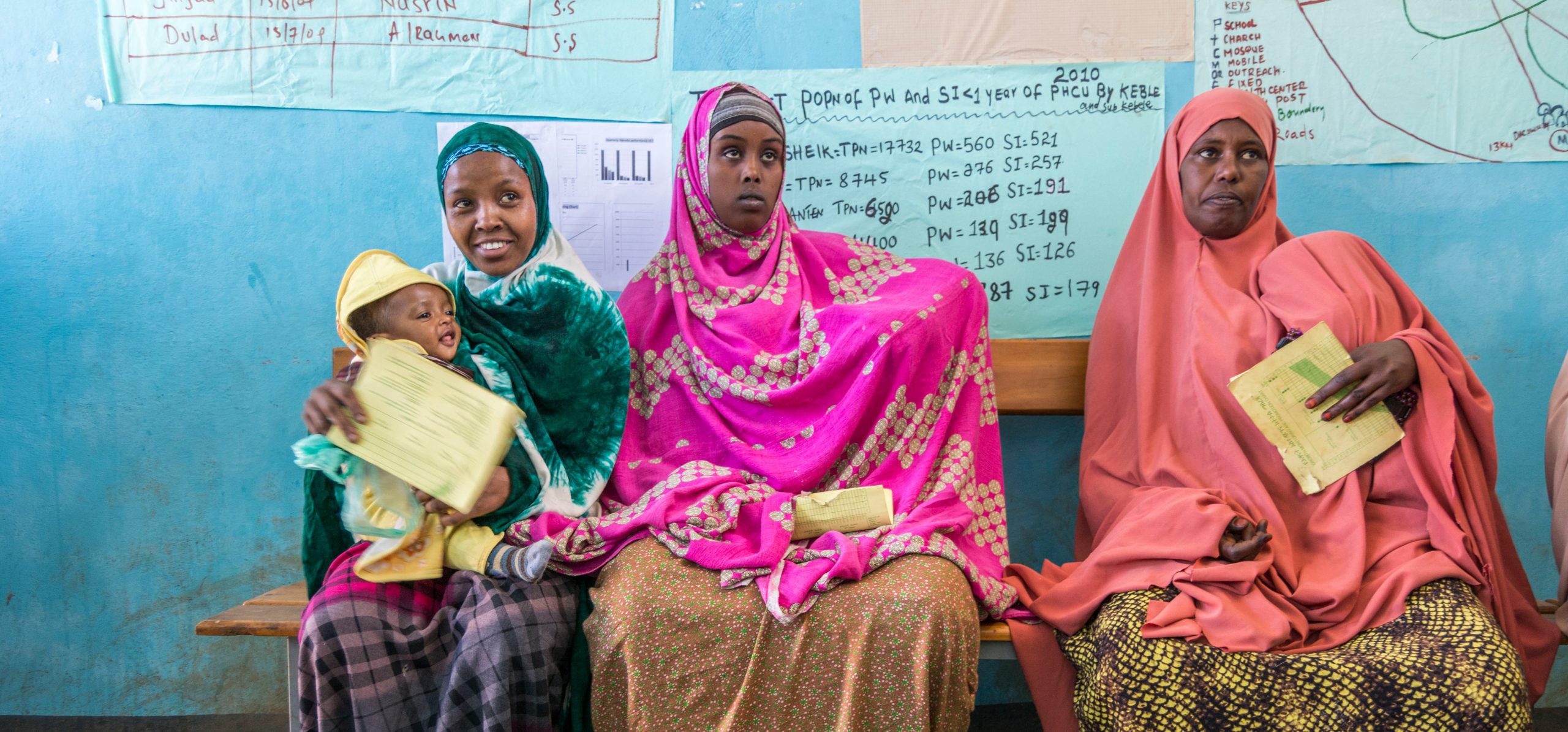 Three women and a baby sitting in a health facility