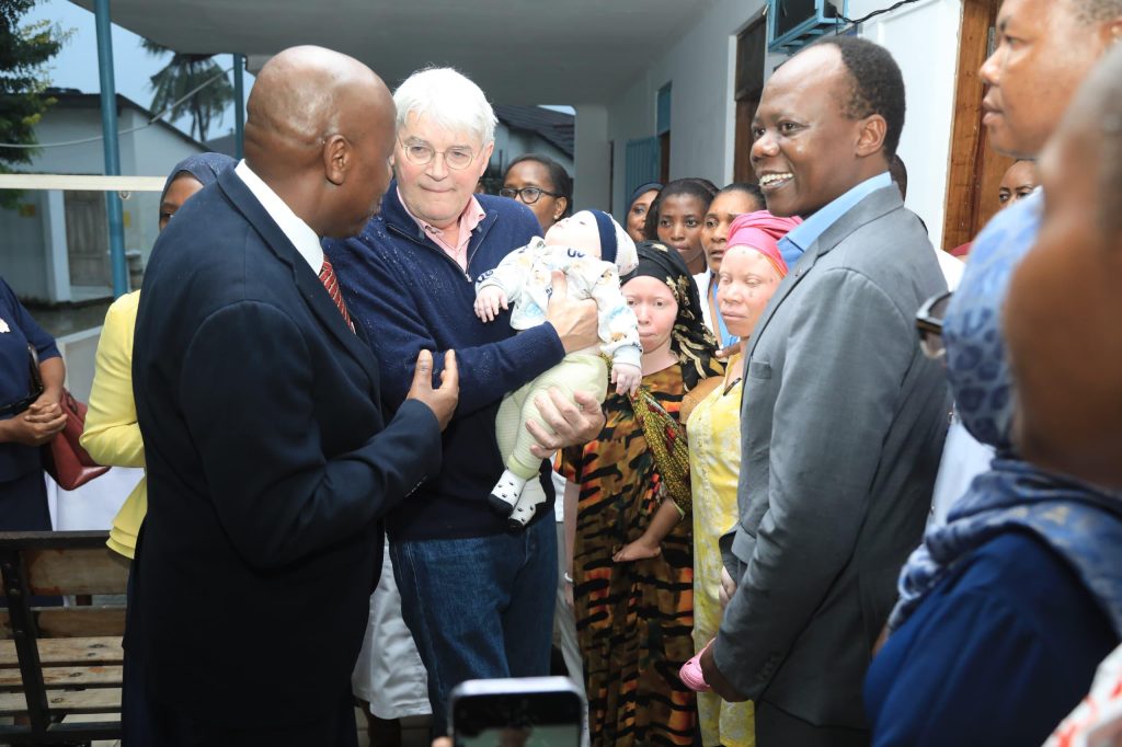 UK Minister Andrew Mitchell holding a baby during a visit to Tanzania
