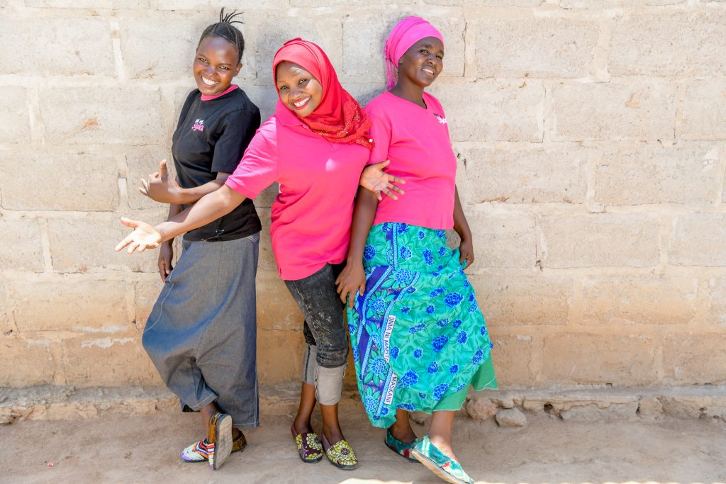 Three smiling girls in bright clothes in Tanzania