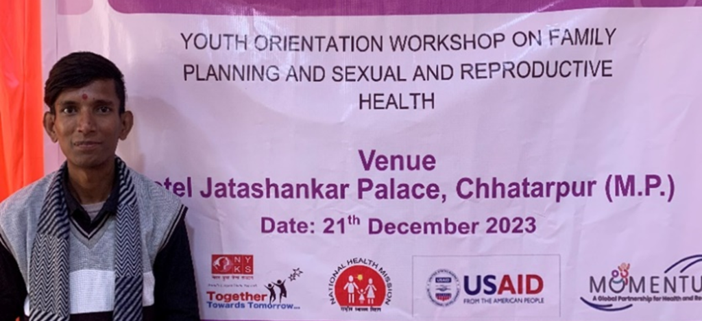 Young man standing in front of a banner that says "Youth Orientation Workshop on Family Planning and Sexual and Reproductive Health"