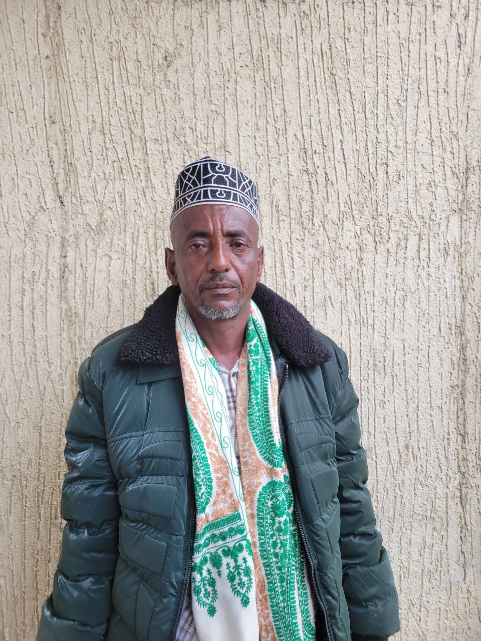 An Ethiopian man stands against a wall.