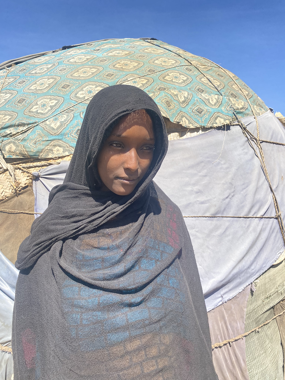 Ergo Humed, an Ethiopian mother, stands in front of her home.