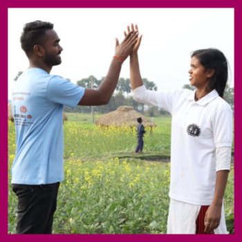 Two Indian teens -- Nitu and Prashant -- high-five in a field.