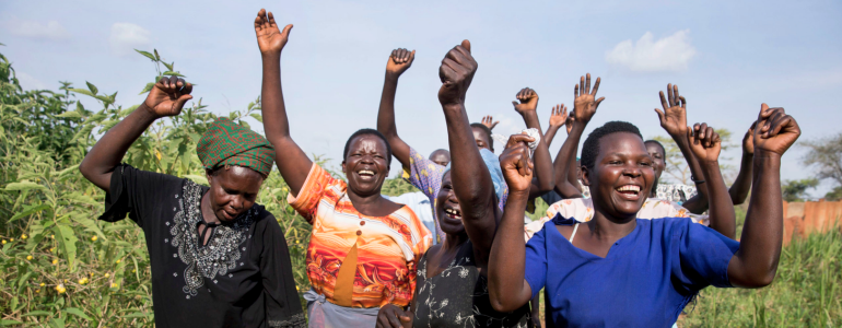 Group of women raise hands in celebration.