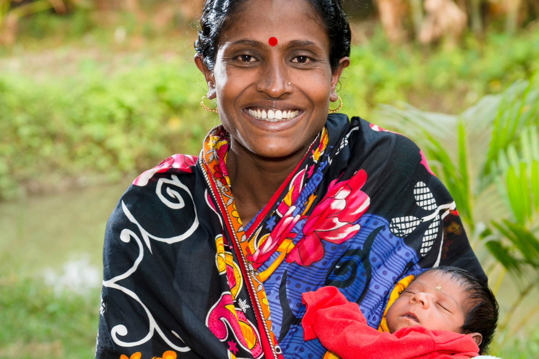 Indian mother smiles while holding her newborn