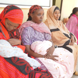Photo of three mothers holding their babies while waiting for care outside a clinic in Ethiopia.